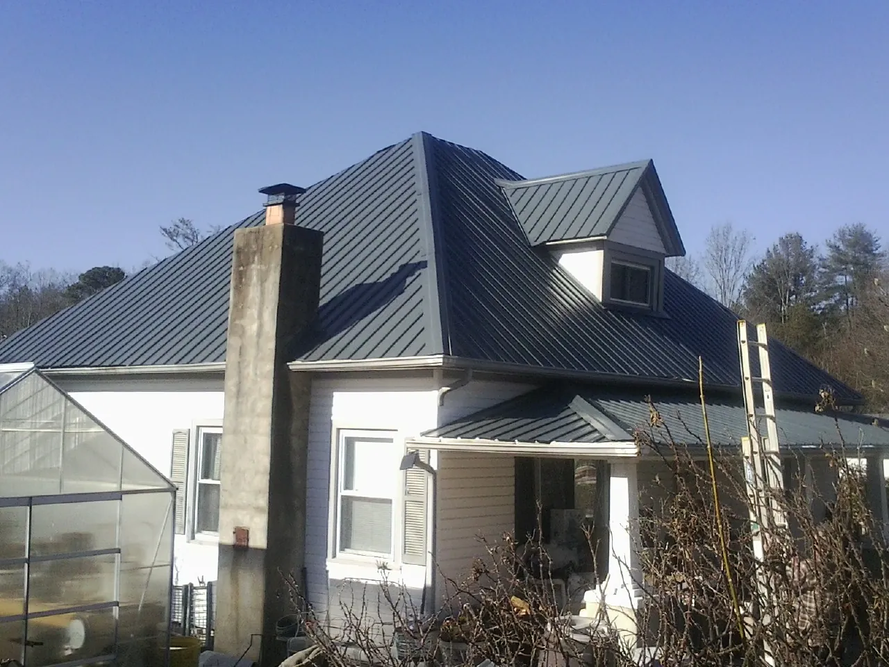 Dark blue standing seam metal roof on a white farmhouse with dormer — Slate & Tile Roof Repair by Roofing Brothers in Big Bear Lake