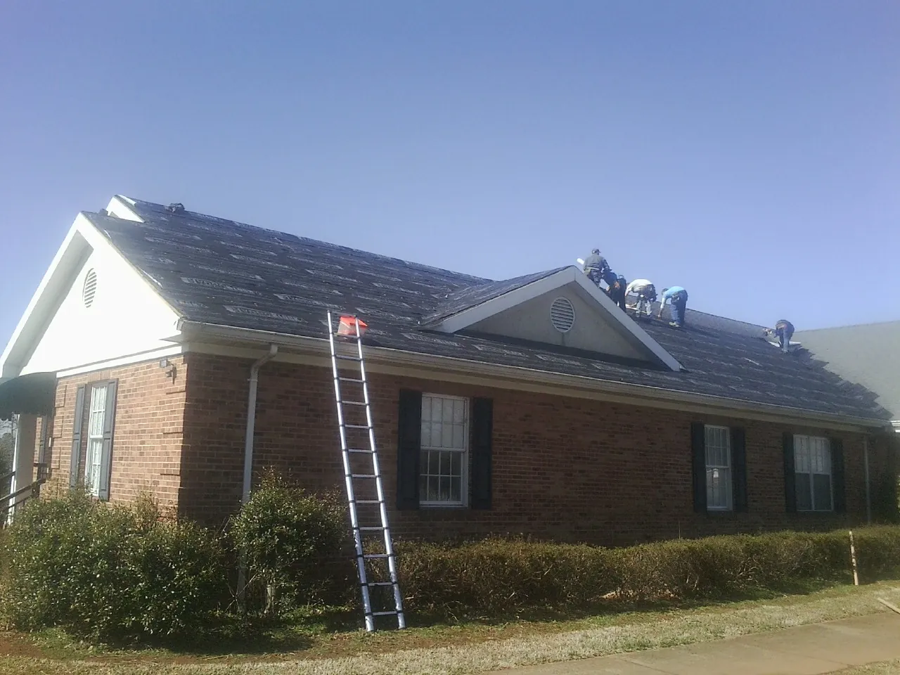 Crew tearing shingles off a brick ranch roof with a ladder set — Metal Roof Repair work by our crew in Big Bear Lake