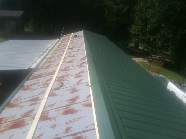 Old rusted panels beside newly installed green metal roofing — Wind Damage Roof Repair by Roofing Brothers in Big Bear Lake