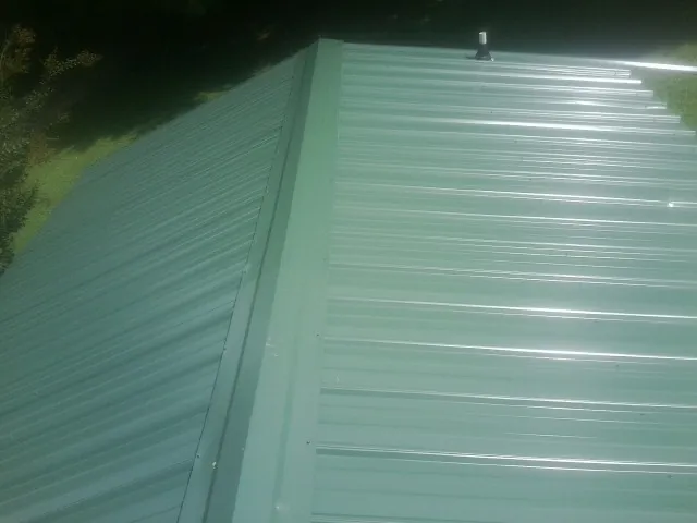 New green metal panels meeting at the ridge of a roof — Flat Roof Repair work by our crew in Big Bear Lake