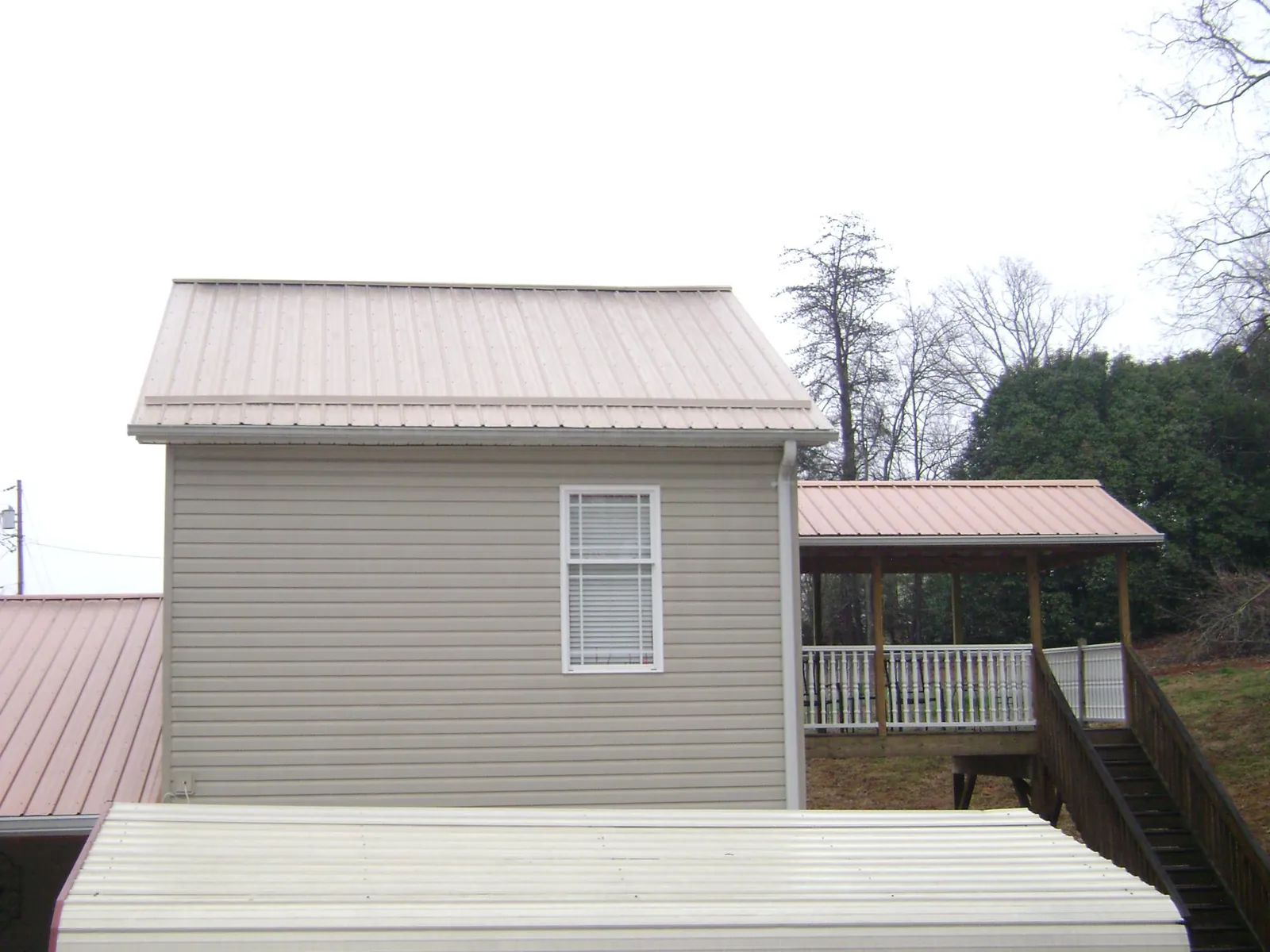 Tan metal roofs on a two story addition and attached porch, from a Roof Replacement job in Big Bear Lake