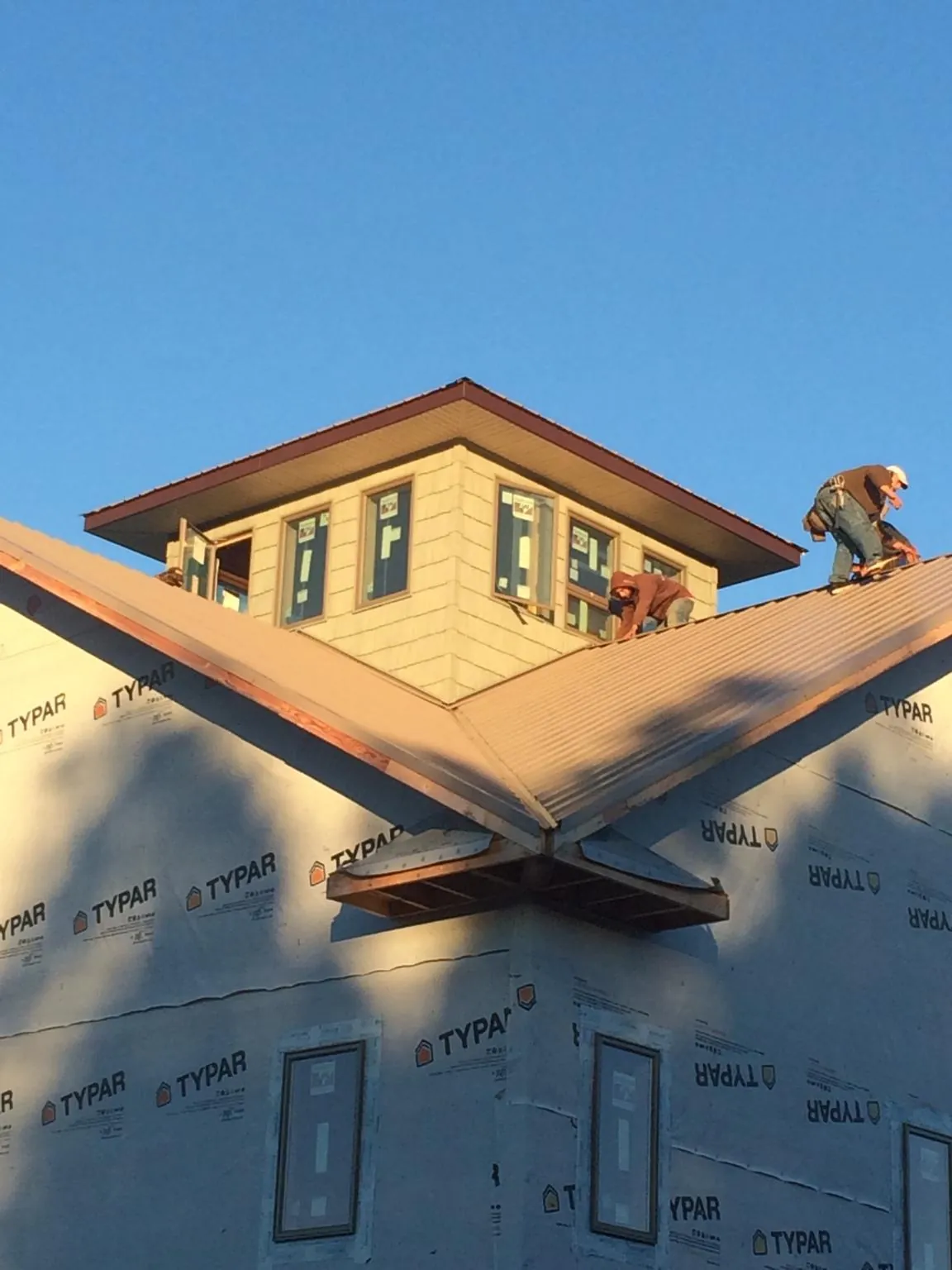 Roofers working around a rooftop cupola on a new metal roof at sunset — Roof Waterproofing in Big Bear Lake by Roofing Brothers
